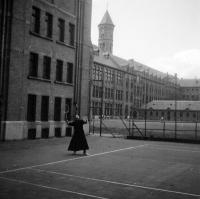 Etterbeek Un jésuite joue au tennis. A l'arrière la chaufferie et l'ancienne salle de gym